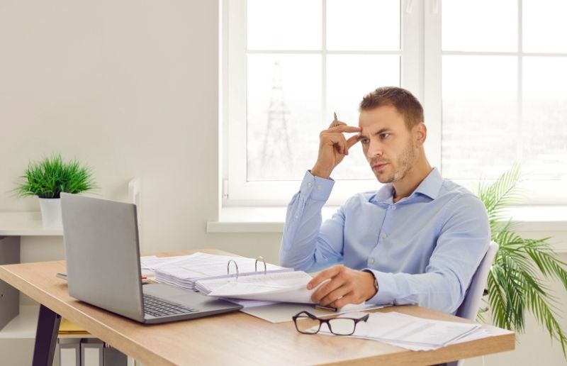 Person reviewing documents and laptop, researching EV charger specifications