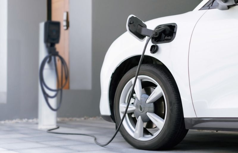 White electric vehicle charging at a wall-mounted Level 2 home charger